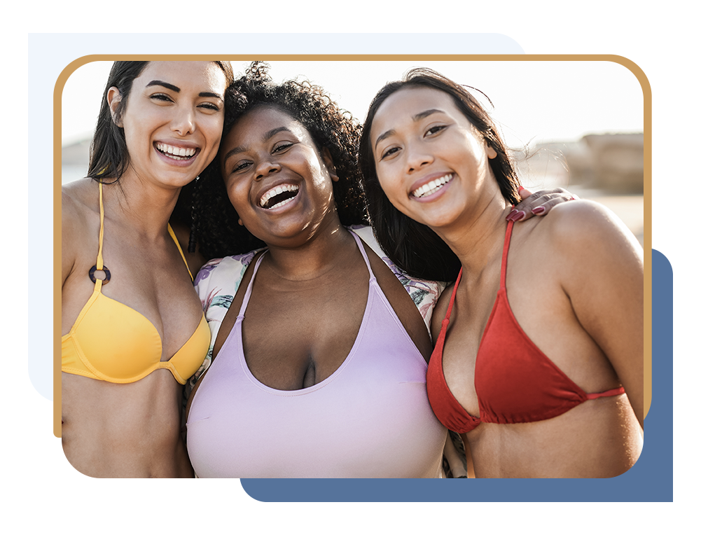 Three women posing for a photo in swimwear at a beach