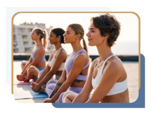 A group of smiling women sitting in a row on yoga mats