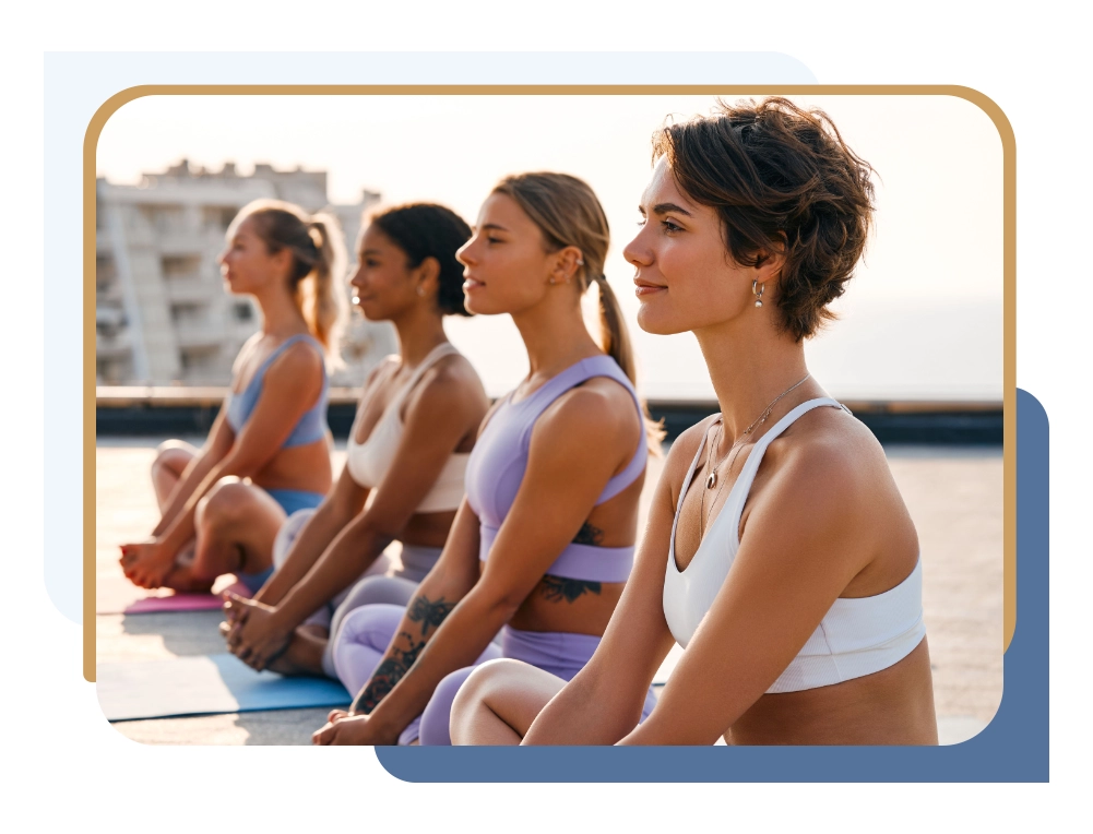 A group of smiling women sitting in a row on yoga mats